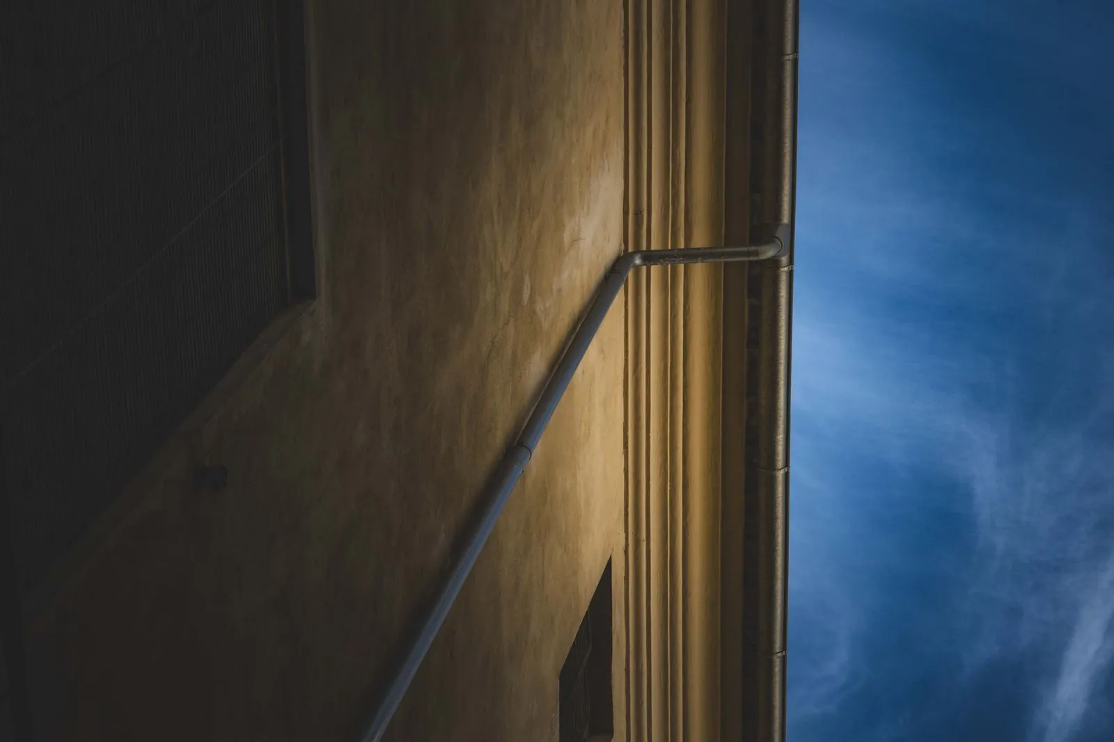 Stylized architectural shot of a building facade against a bright blue sky.